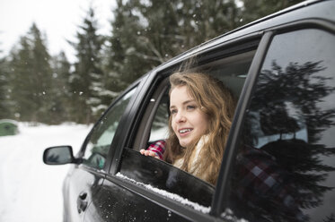 Young woman looking out of a car window in winter landscape - HAPF02067