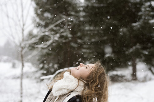 Glückliche junge Frau genießt den Schneefall im Winterwald - HAPF02072