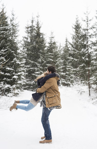 Glückliches junges Paar hat Spaß im verschneiten Winterwald, lizenzfreies Stockfoto