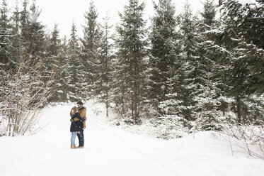 Glückliches junges Paar steht sich im verschneiten Winterwald gegenüber - HAPF02076