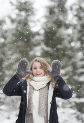 Porträt einer glücklichen jungen Frau bei Schneefall in der Natur - HAPF02077