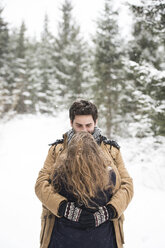Glückliches junges Paar, das sich in einer Winterlandschaft umarmt - HAPF02080