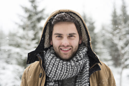 Porträt eines lächelnden jungen Mannes im Winter - HAPF02089