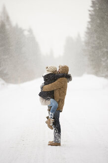 Glückliches junges Paar von Angesicht zu Angesicht in schneebedeckter Winterlandschaft - HAPF02094