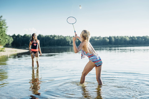 Zwei Freunde spielen Federball am Seeufer, lizenzfreies Stockfoto