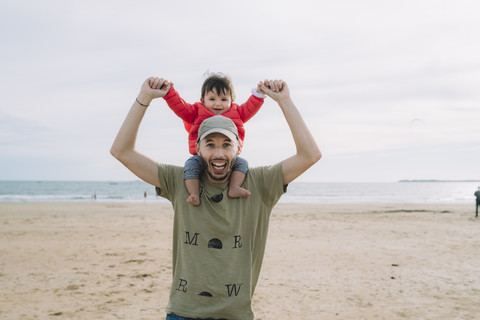 Porträt eines Vaters, der seine kleine Tochter auf den Schultern am Strand trägt, lizenzfreies Stockfoto