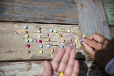 Hand placing chocolate drops on table - MOEF00070