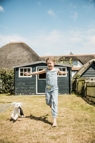 Mädchen läuft mit Hund im Garten, lizenzfreies Stockfoto