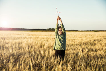 Girl standing in grain field holding miniature wind turbine - MOEF00093