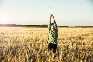 Mädchen steht in einem Getreidefeld und hält ein Miniatur-Windrad - MOEF00093