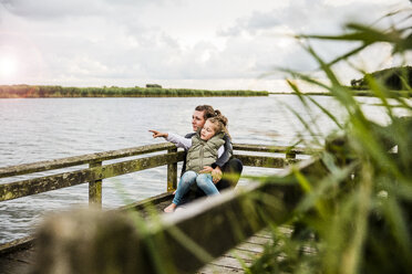 Mother and daughter on jetty at a lake - MOEF00106