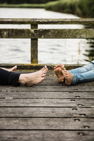 Füße von Mutter und Tochter auf einem Steg an einem See, lizenzfreies Stockfoto