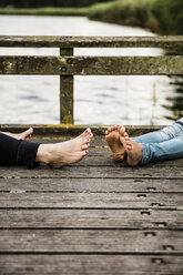 Feet of mother and daughter on jetty at a lake - MOEF00107