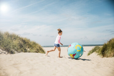 Girl playing with globe on the beach - MOEF00121