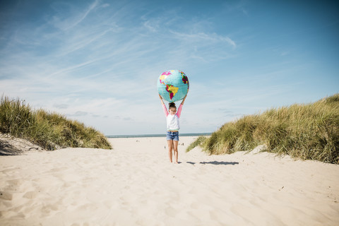Mädchen hält Globus am Strand, lizenzfreies Stockfoto