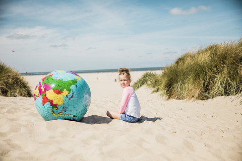 Mädchen mit Globus am Strand, lizenzfreies Stockfoto