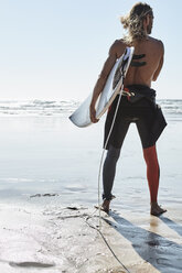 Portugal, Algarve, Mann am Strand mit Surfbrett - JRF00322