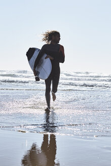 Portugal, Algarve, Mann läuft mit Surfbrett im Wasser - JRF00323