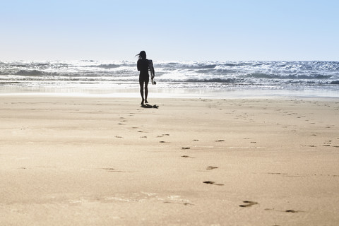 Portugal, Algarve, Mann am Strand mit Surfbrett, lizenzfreies Stockfoto