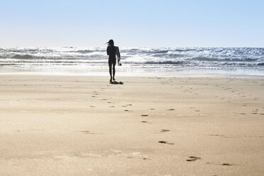 Portugal, Algarve, Mann am Strand mit Surfbrett - JRF00326