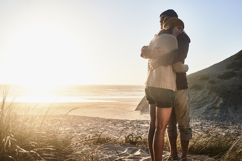 Portugal, Algarve, Paar umarmt sich bei Sonnenuntergang am Strand, lizenzfreies Stockfoto