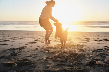 Portugal, Algarve, Frau mit Hund am Strand bei Sonnenuntergang - JRF00342