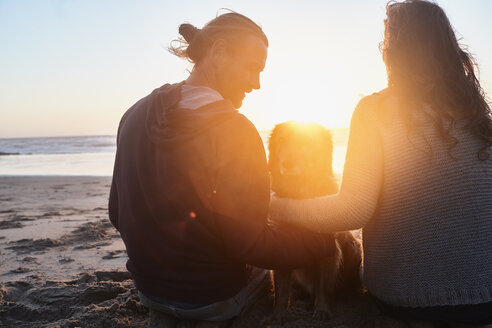 Portugal, Algarve, Paar mit Hund am Strand bei Sonnenuntergang - JRF00343