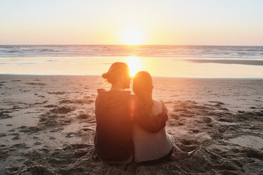 Portugal, Algarve, couple sitting on the beach at sunset - JRF00346