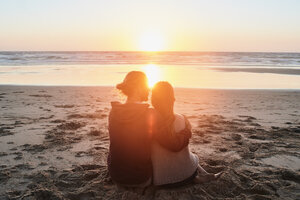 Portugal, Algarve, Paar am Strand sitzend bei Sonnenuntergang - JRF00346