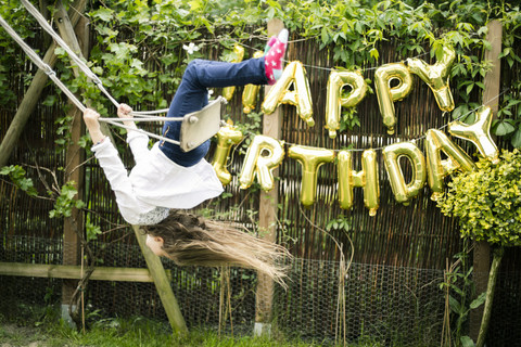 Girl swinging head first in the garden stock photo