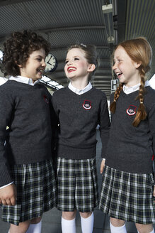 Drei Mädchen in Schuluniform unterhalten sich auf dem Bahnsteig - FSF00946