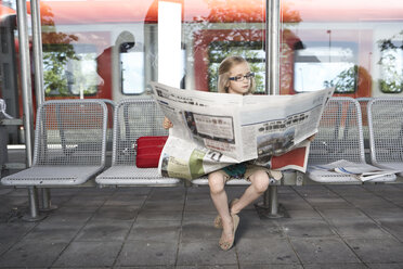 Porträt eines kleinen Mädchens, das am Bahnsteig sitzt und Zeitung liest - FSF00947