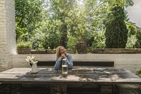 Ältere Frau sitzt auf der Terrasse und genießt den Sommer - RIBF00679