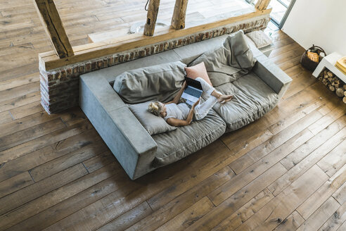 Woman lying on couch, using laptop - RIBF00706