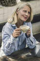 Mature woman sitting on terrace, drinking tea - RIBF00716