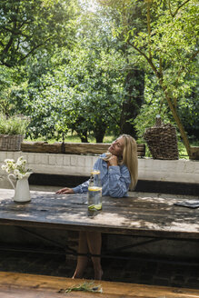 Mature woman sitting on terrace, enjoying summer - RIBF00725
