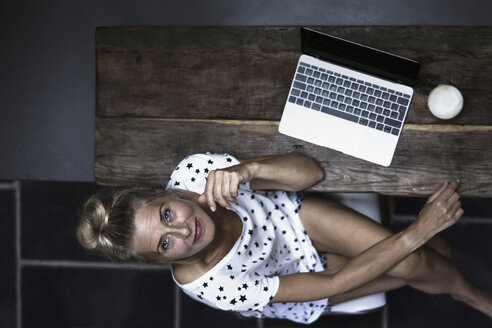 Woman sitting in kitchen, using laptop - RIBF00760