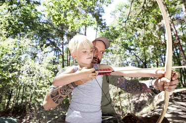 Vater und Sohn schießen mit Pfeil und Bogen im Wald - MFRF00988