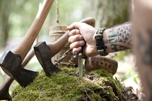 Äxte, Baumstumpf und Hand mit Messer im Wald - MFRF00994