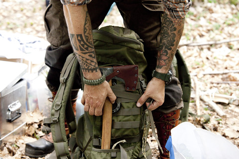 Mann mit Axt und Rucksack im Wald, lizenzfreies Stockfoto