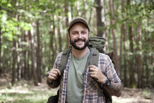 Porträt eines lächelnden Mannes mit Rucksack bei einer Wanderung im Wald - MFRF01016