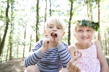 Junge und Mädchen im Wald essen herzförmiges Laugengebäck - MFRF01028