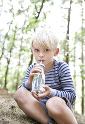 Boy drinking from glass of infused water in forest - MFRF01035