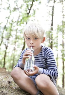 Junge trinkt im Wald aus einem Glas mit aufgegossenem Wasser - MFRF01035