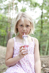 Mädchen trinkt im Wald aus einem Glas mit aufgegossenem Wasser - MFRF01036