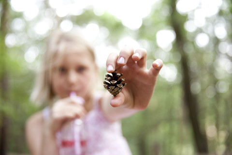 Nahaufnahme eines Mädchens mit Tannenzapfen im Wald, lizenzfreies Stockfoto