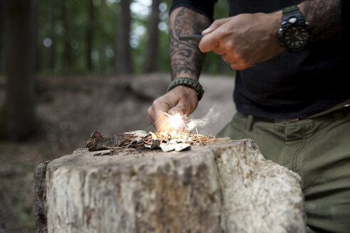 Ein Mann entzündet ein Feuer auf einem Baumstumpf im Wald - MFRF01045