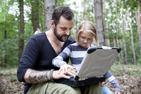 Vater und Tochter im Wald mit Laptop - MFRF01052
