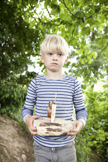 Junge hält geschnitztes Holzboot im Wald - MFRF01056