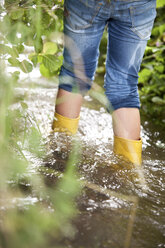 Girl with rubber boots wading in brook - MFRF01061